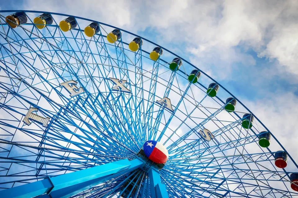 Blue Ferris wheel with Texas state Lone Star logo in middle of wheel.